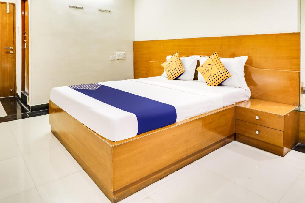 a bedroom with a large bed with a wooden headboard at SPOT ON Srinivasa Residency in Tirupati