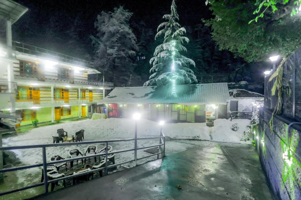 a building with a christmas tree in the snow at Luvya Retreats Hotel in Manāli