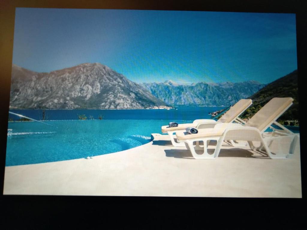 duas cadeiras sentadas numa praia junto à água em Pool and spa apartment 1BR em Donji Morinj