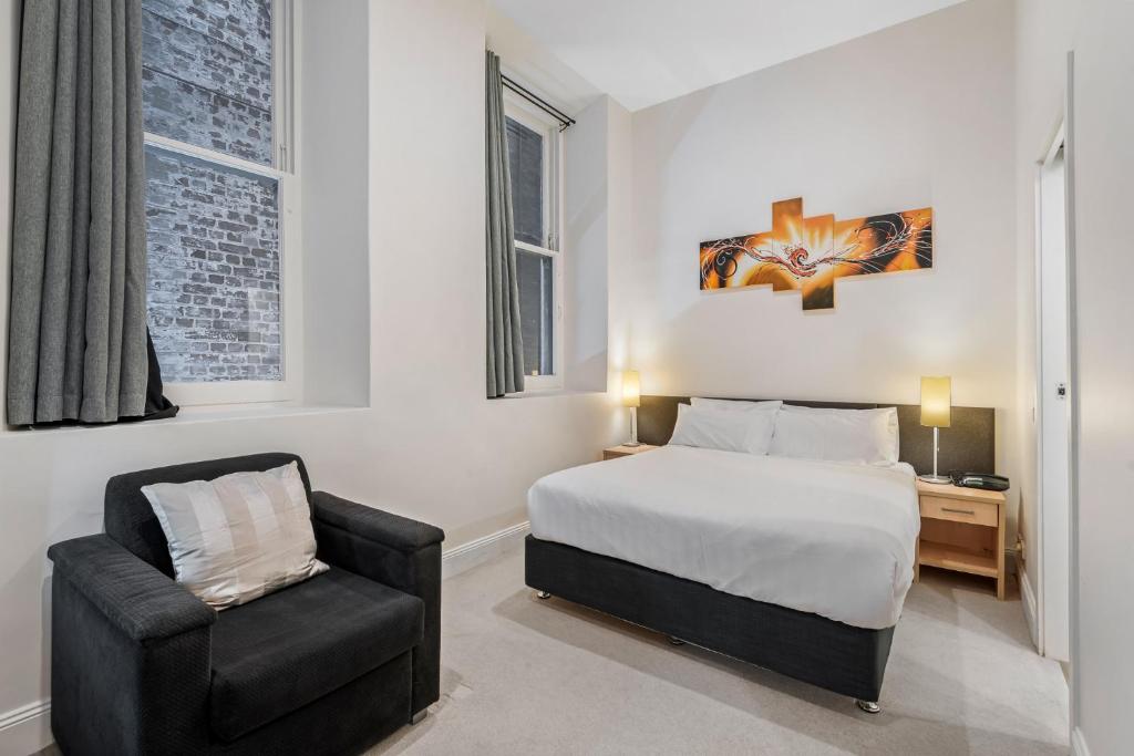 - une chambre avec un lit et une chaise dans l'établissement Studio Gem in the Heart of Melbourne, à Melbourne