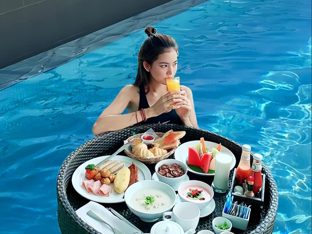 a woman sitting in a pool with a tray of food at Central Hotel Danang in Da Nang