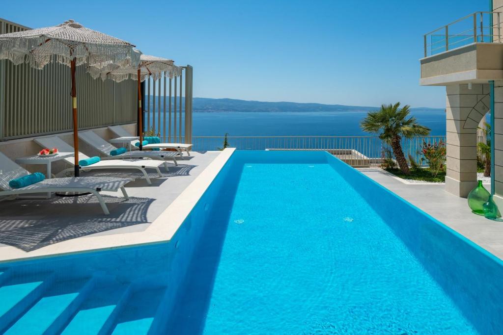 a large blue swimming pool with chairs and umbrellas at New! Casa GENI-heated pool, 3 bedrooms, sea views in Omiš