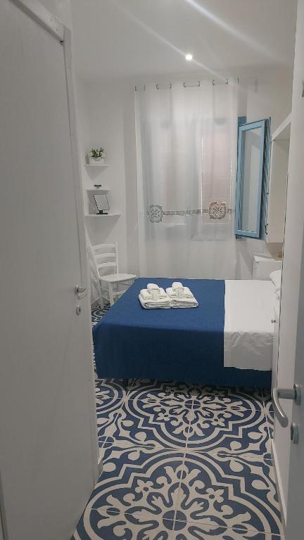 Un dormitorio con una cama azul y blanca y un baño. en Benvenuti al Sud B&B, en Macari