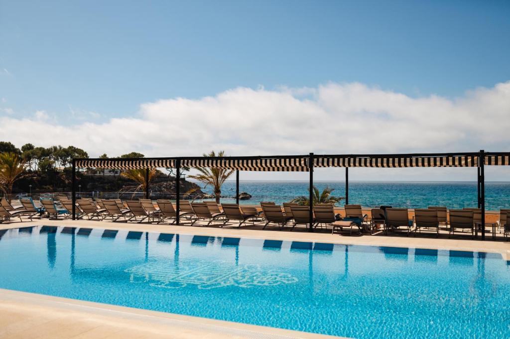 basen z krzesłami i ocean w tle w obiekcie Secrets Mallorca Villamil Resort & Spa - Adults Only (+18) w mieście Paguera