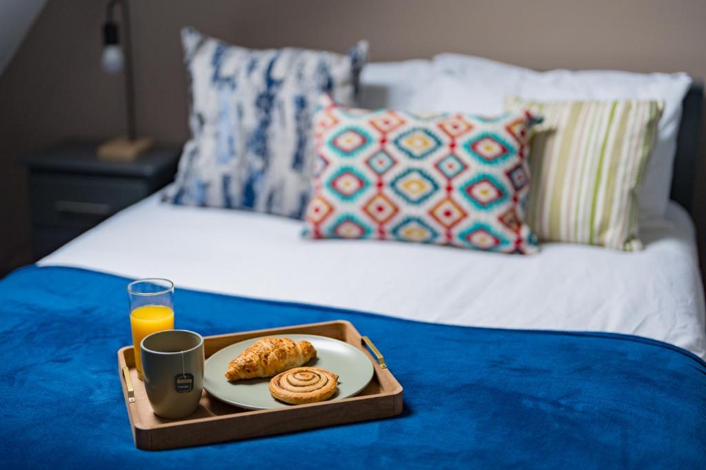 a tray of food and a glass of orange juice on a bed at Entire apartment near NEC, Birmingham Airport BHX, Resorts World, HS2, JLR, Solihull Hospital in Sheldon