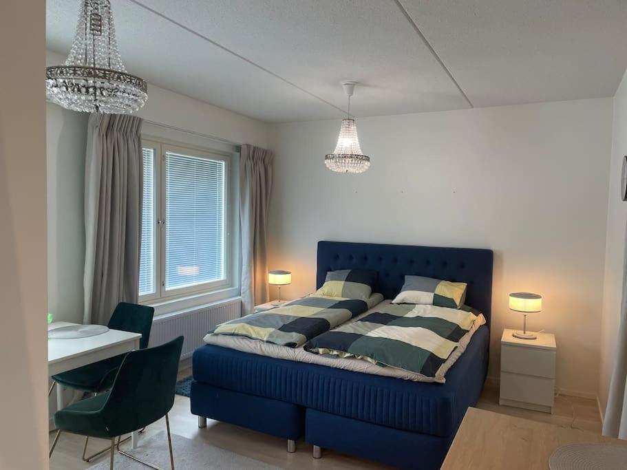 een slaapkamer met een blauw bed en een tafel en stoelen bij A studio near to Airport in Vantaa