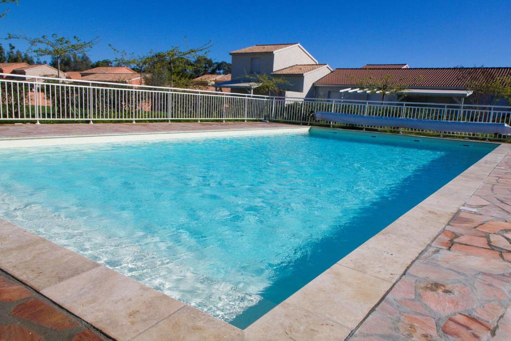 ein Pool mit blauem Wasser vor einem Zaun in der Unterkunft Villa climatisée T3 piscine chauffée accès direct à la plage de Prunete in Cervione
