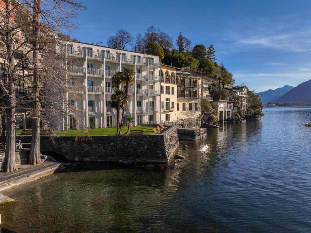 un grande edificio sul lato di un fiume di Casa Moscia ad Ascona