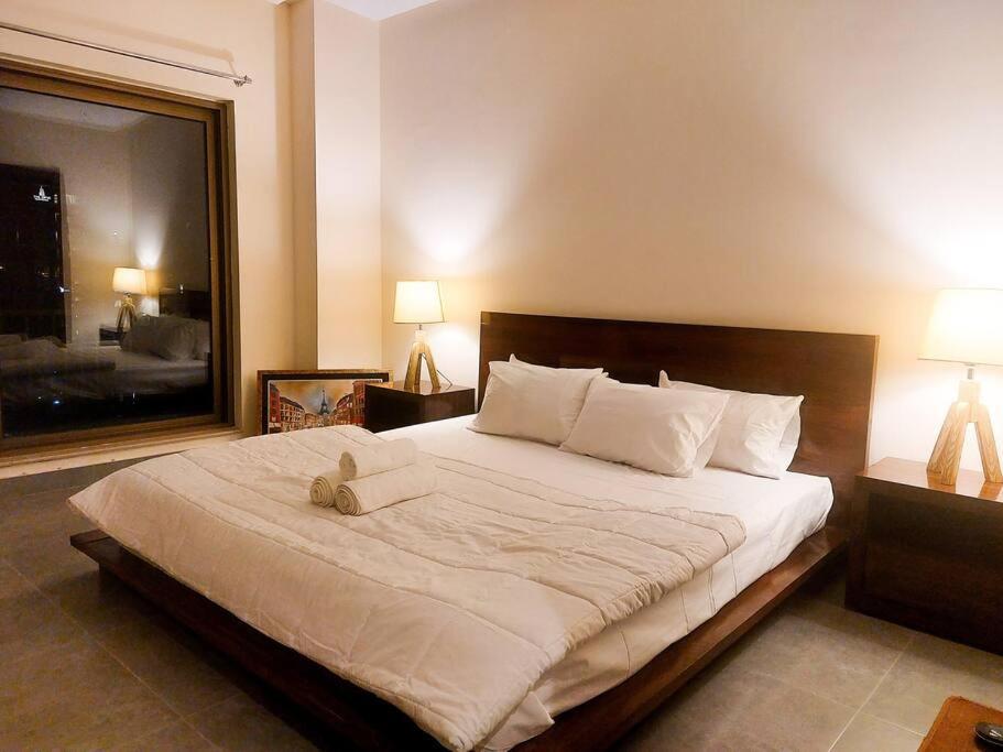 um quarto com uma cama grande e uma janela grande em Premium 1bed apt CNTRL Minimal and cozy em Lahore