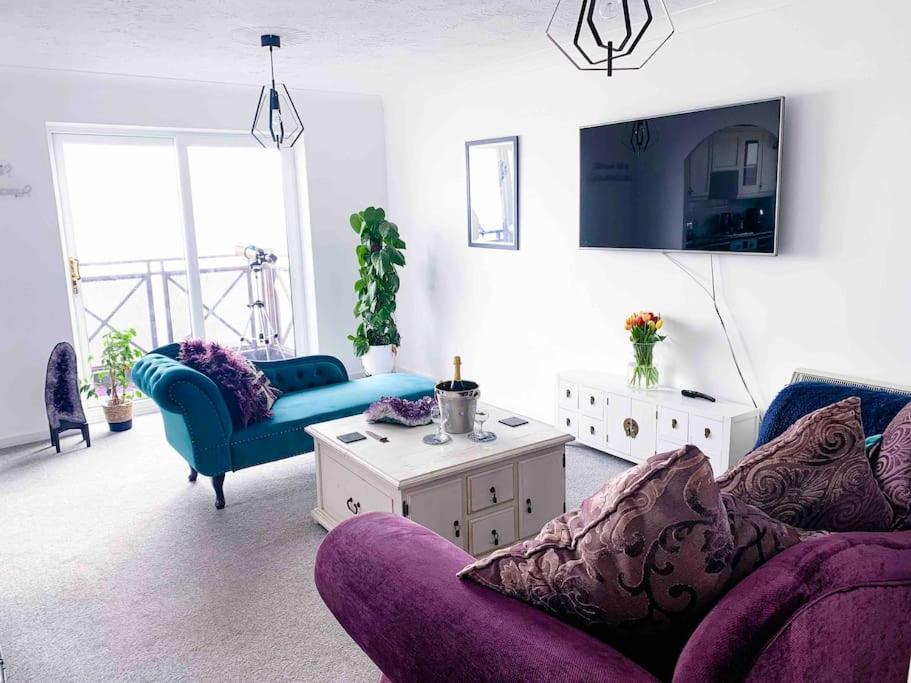 a living room with purple furniture and a tv at Beachfront Artsy Apartment in Clacton-on-Sea