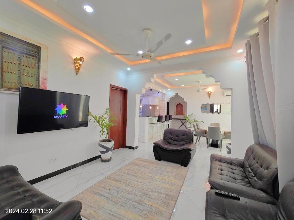 a living room with couches and a flat screen tv at Ayaa Luxury Apartment 3rd Floor Zanzibar in Ngambo