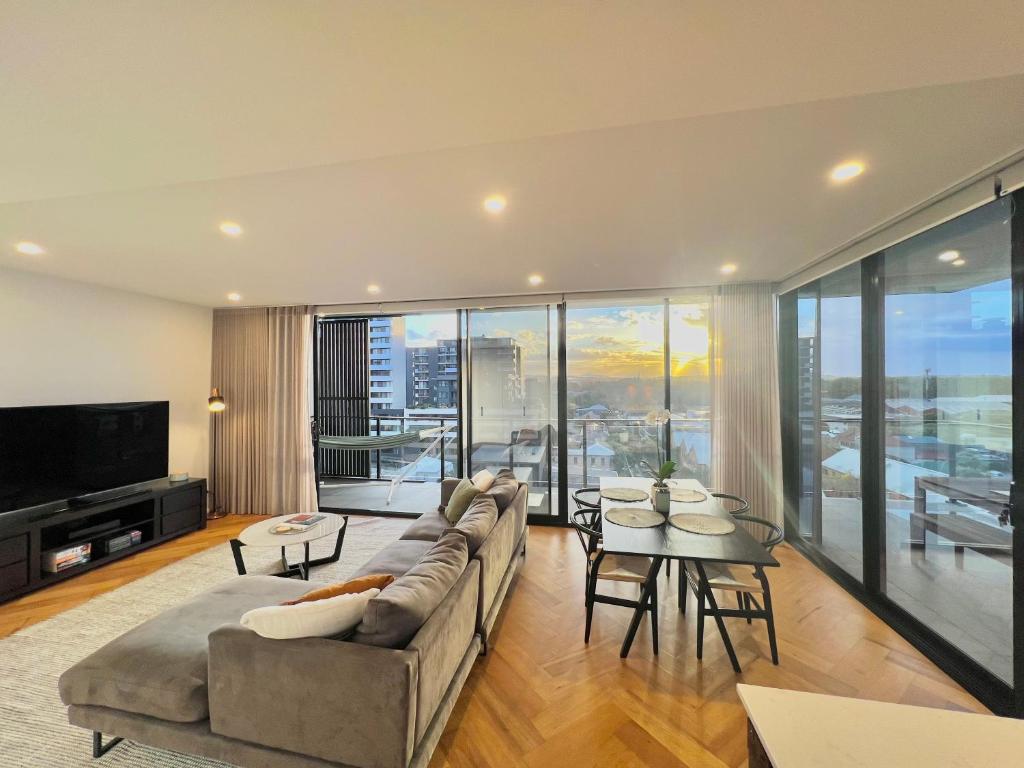 a living room with a couch and a table and chairs at Harbour Towers, Newcastle's Luxe Apartment Stays in Newcastle