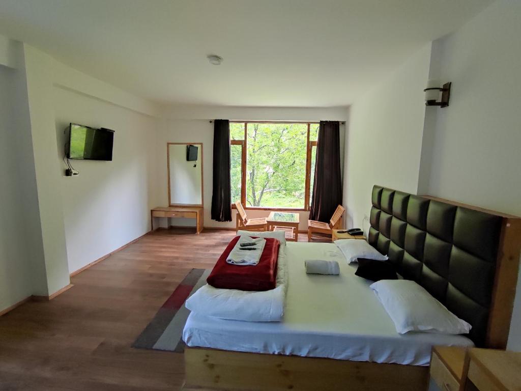 een slaapkamer met een groot bed in een kamer bij New Chandra Bhaga Guest House in Manāli