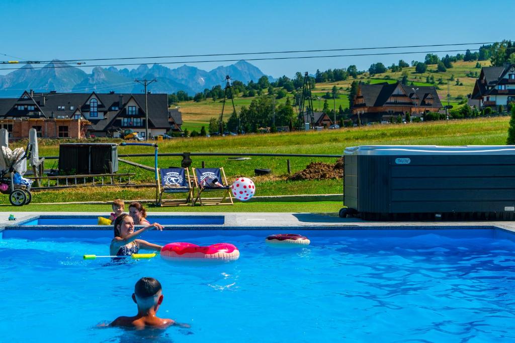 un grupo de niños jugando en una piscina en Aparthotel Rabiań-SKI zewnętrzny basen oraz jacuzzi z podgrzewana wodą dmuchaniec i 2 place zabaw w cenie en Białka Tatrzanska