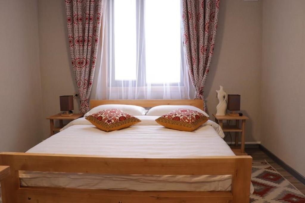 a bedroom with a bed with two pillows and a window at Salamat Hotel in Bishkek