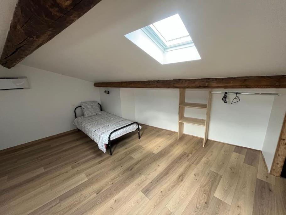 um quarto no sótão com uma cama e uma janela em Charmant duplex rénové à neuf em La Voulte-sur-Rhône