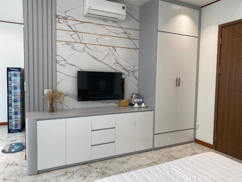 uma sala de estar com televisão e armários brancos em Mia homestay - Vinhomes Ocean Park 2 - 3 em Hòa Bình
