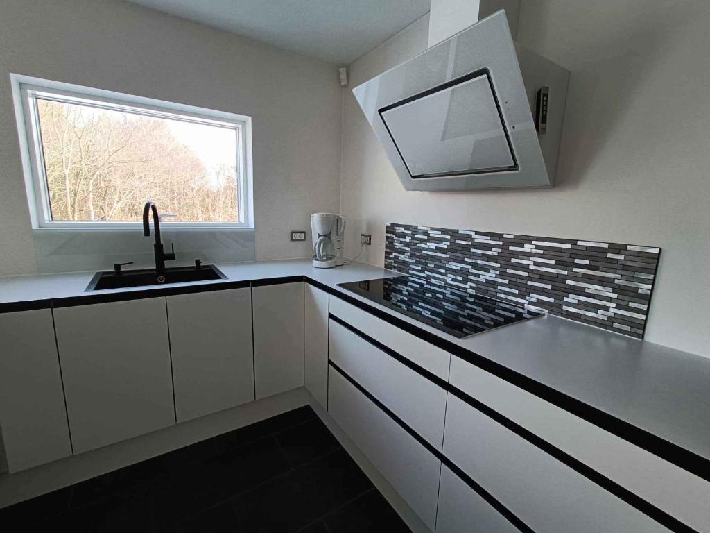 eine weiße Küche mit einem Waschbecken und einem Fenster in der Unterkunft Holiday Home In Blokhus in Blokhus