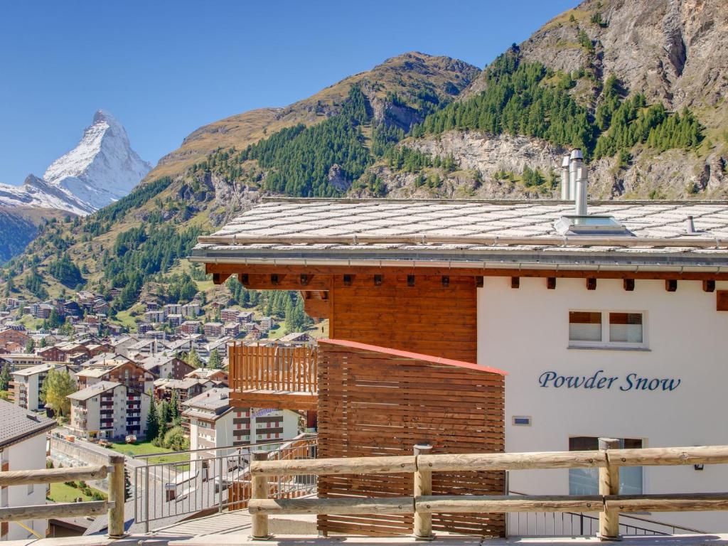 a building with a balcony with a mountain in the background at Haus Powder Snow in Zermatt