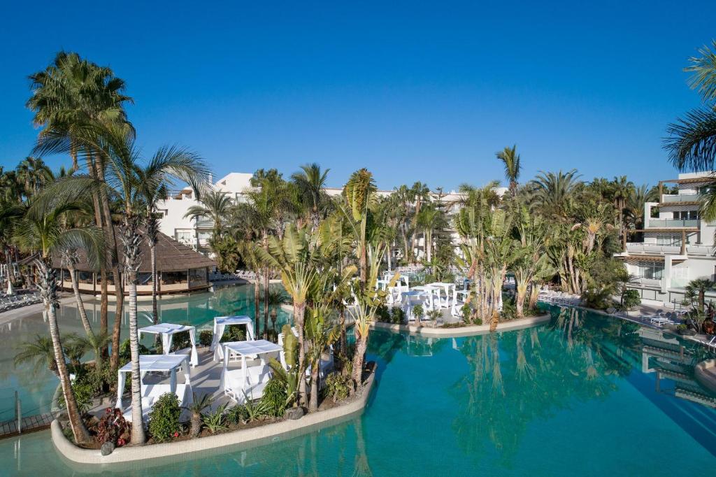 an aerial view of a resort pool with palm trees at Maspalomas Princess in Maspalomas