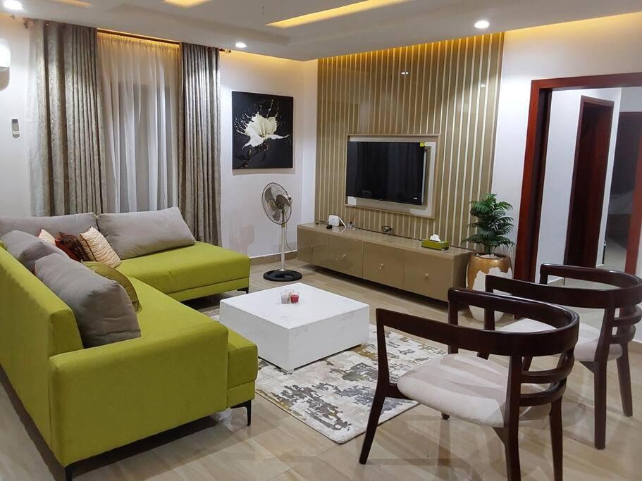 ein Wohnzimmer mit einem gelben Sofa und einem TV in der Unterkunft Comfort and Style. in Benin-Stadt