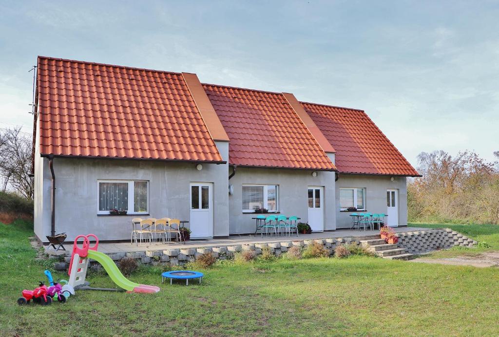 uma casa com um telhado laranja e um parque infantil em Apartmány Vinařství Klučov em Lstiboř