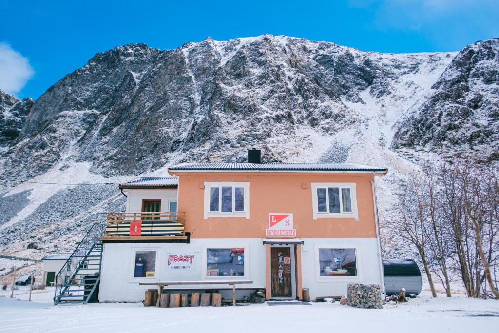 a building in front of a snow covered mountain at Unstad Surfpacker in Unstad