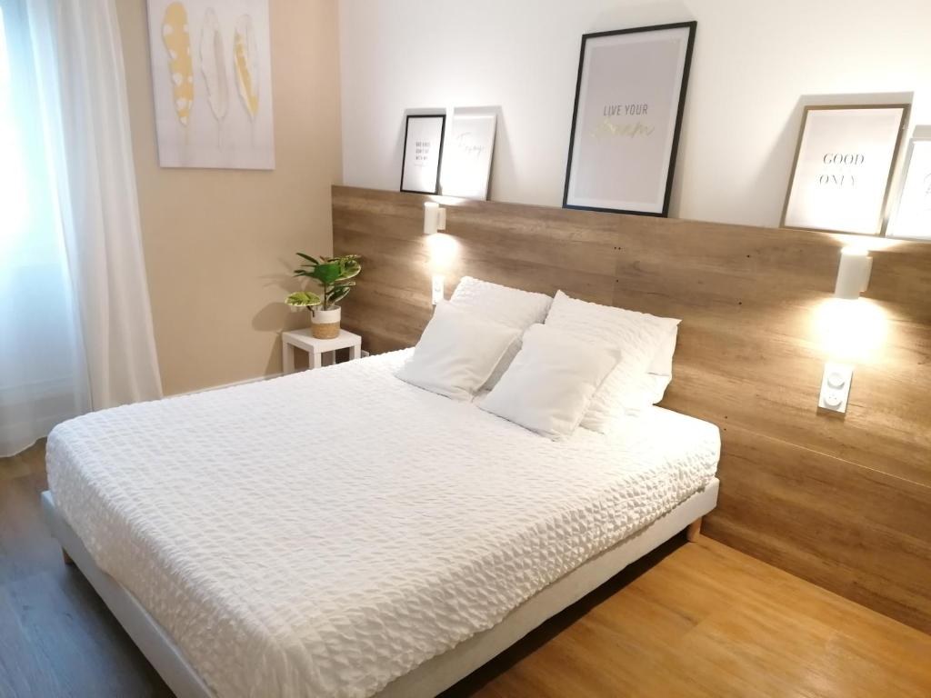 une chambre avec un lit blanc avec une tête de lit en bois dans l'établissement T2 centre ville Antigone Piscine Tennis, à Montpellier