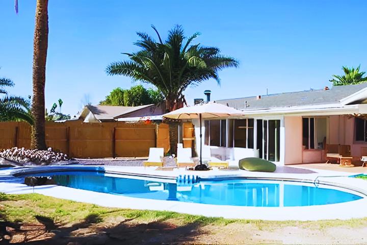 een zwembad met een parasol en een huis bij Spacious 5BR Oasis with Heated Pool - Perfect for Family in Mesa