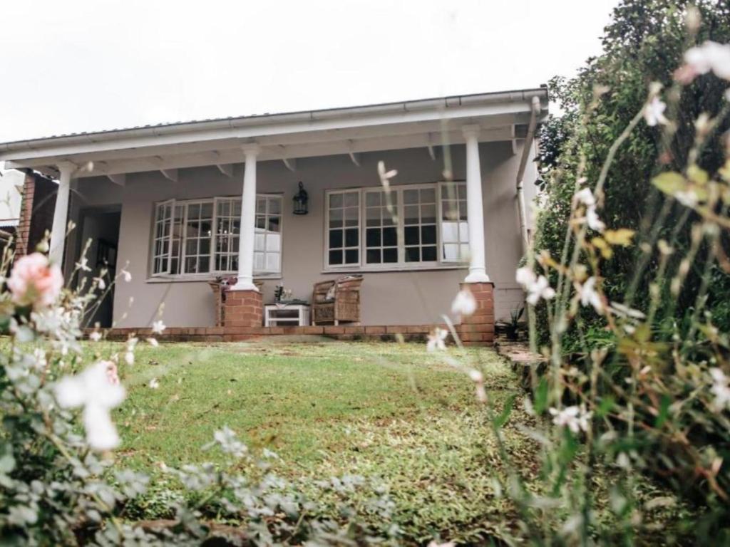 ein kleines Haus mit Rasen davor in der Unterkunft Wylde Rose Cottage in Pietermaritzburg