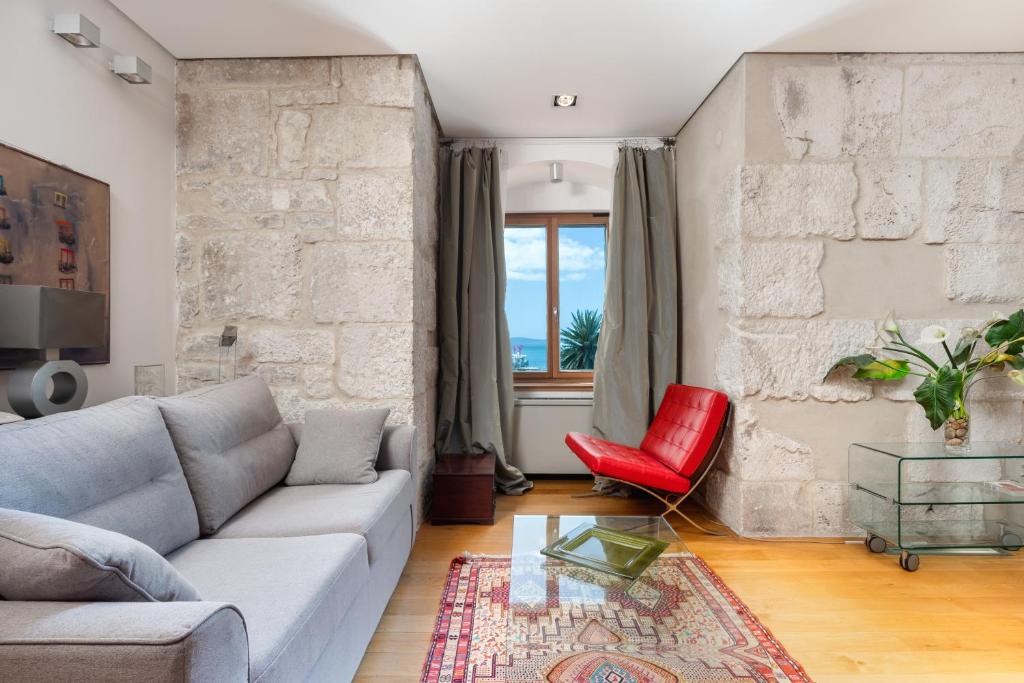een woonkamer met een bank en een rode stoel bij Imperial suite in Split