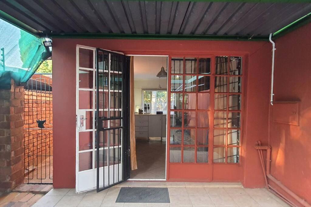 une porte ouverte menant à une maison avec une porte rouge dans l'établissement Garden flat for working person, à Pierre van Ryneveld