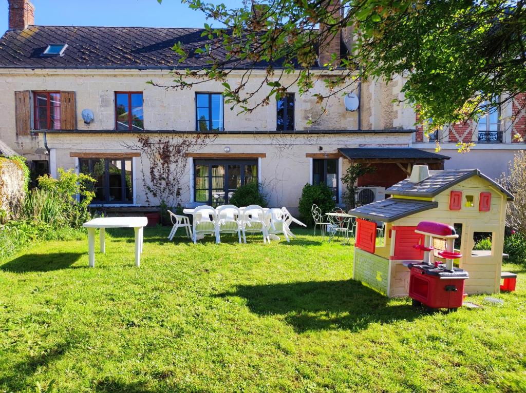 una casa de juegos en el césped delante de una casa en Gîte de la vallée à Courdemanche Sarthe en Courdemanche