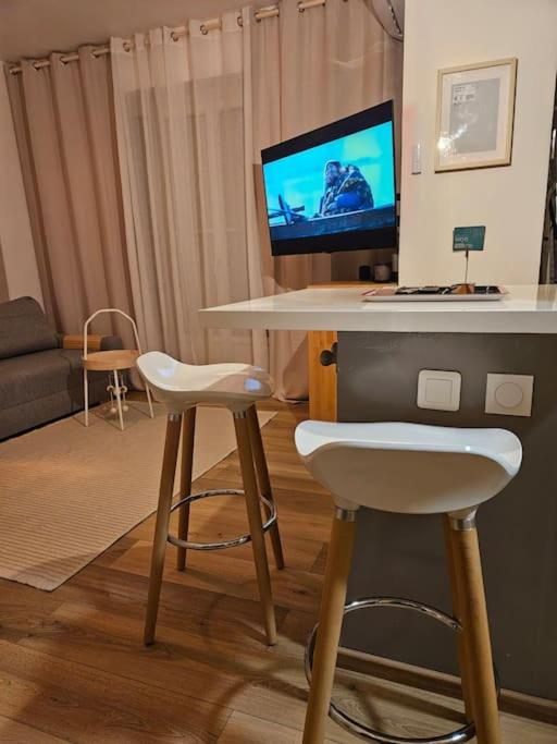 un salon avec une table avec un ordinateur et deux tabourets dans l'établissement Le plein ciel Studio, à Nice