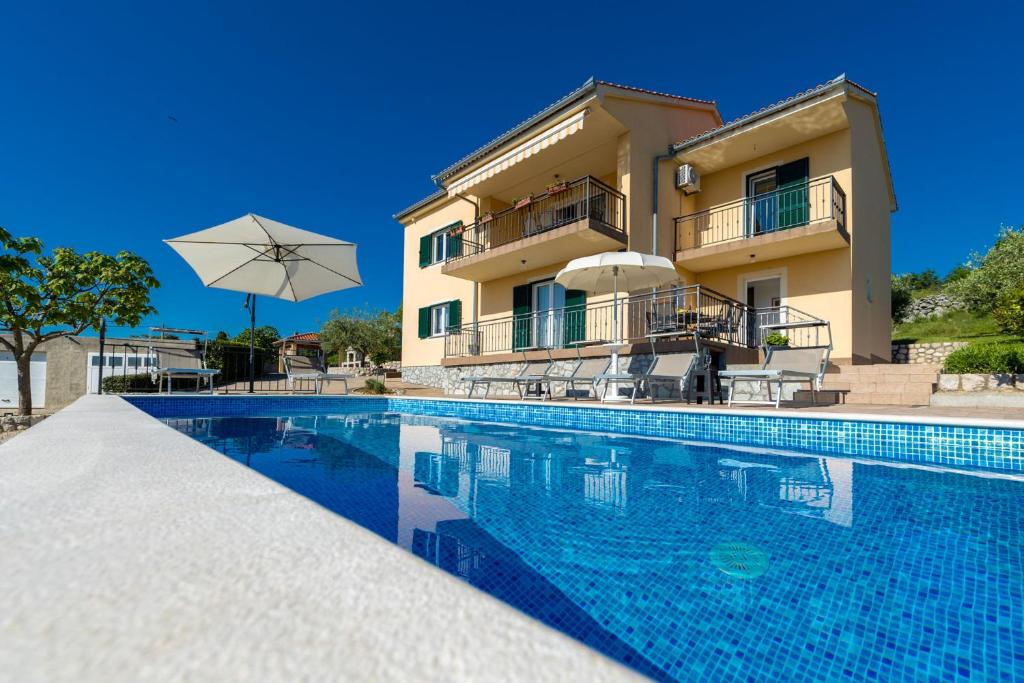 a villa with a swimming pool in front of a building at Apartment Krk David & Matej in Linardići