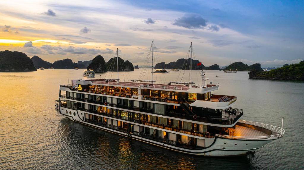 a cruise ship in the water with mountains in the background at La Regina Grand Cruise in Ha Long