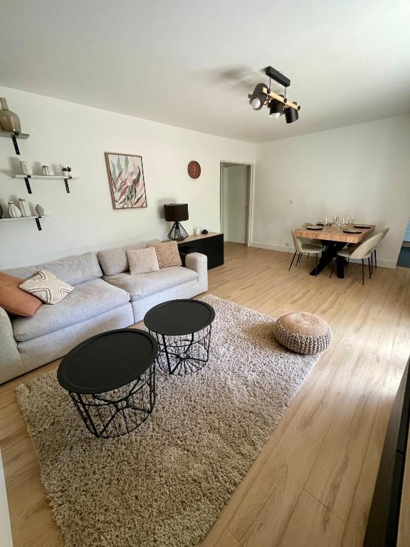 un salon avec un canapé et deux tables dans l'établissement Appartement Cosy Montigny le Bretonneux, à Montigny-le-Bretonneux