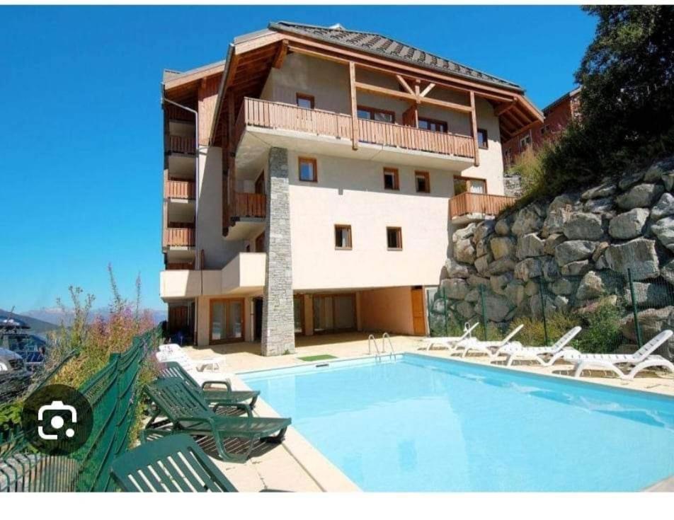 un immeuble avec une piscine devant un immeuble dans l'établissement Valmeinier 1800 Front de neige et piscine d été, à Valmeinier