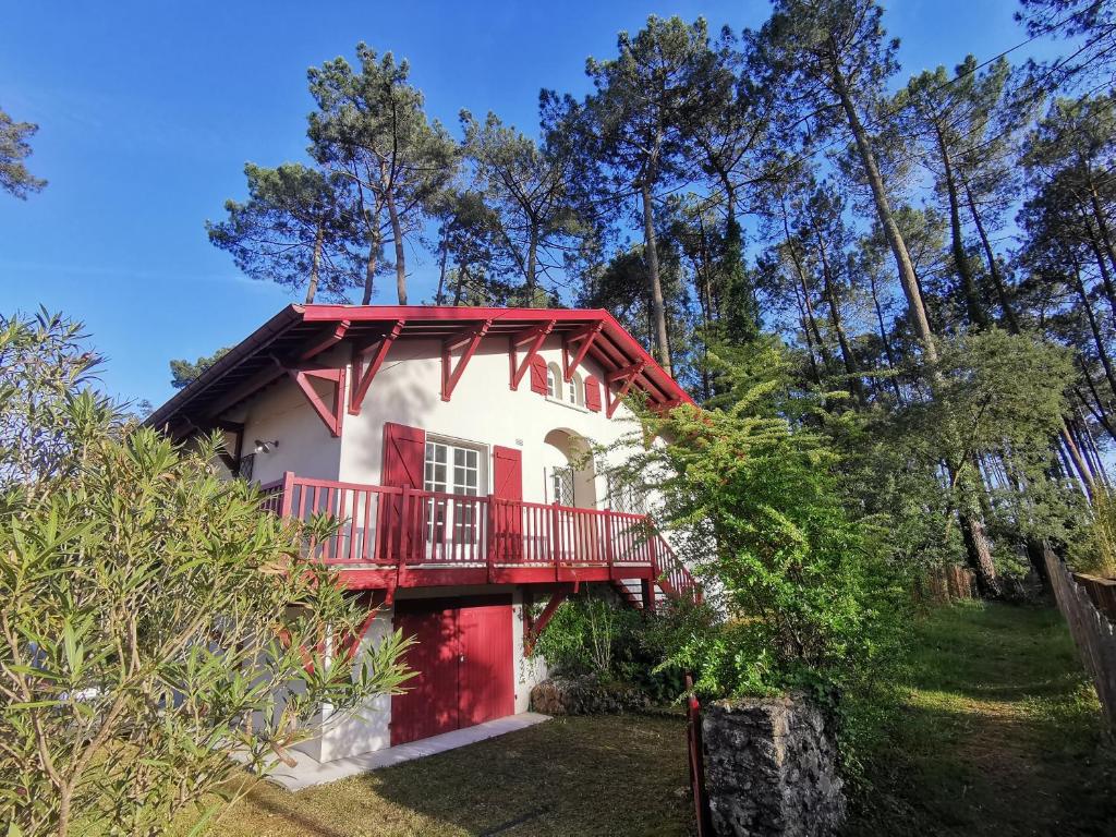 une maison avec une porte rouge et un balcon dans l'établissement Maison Landaise familiale 10 pers au cœur de la forêt, à Seignosse