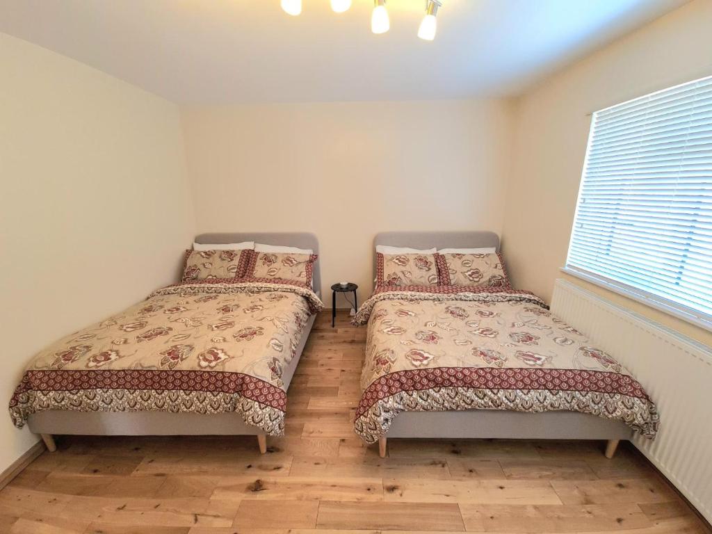two twin beds in a room with a window at London Luxury 2 Bedroom Flat Sleeps 8 free parking in East Barnet