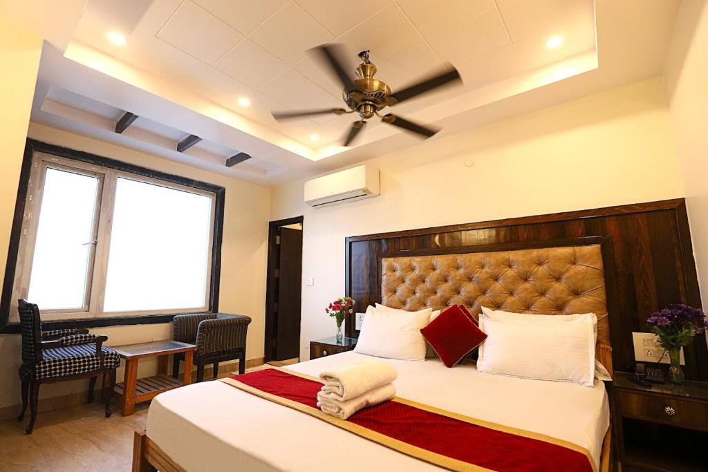 - une chambre avec un grand lit et un ventilateur de plafond dans l'établissement Staybook Hotel Atlanta New Delhi Train Station, à New Delhi
