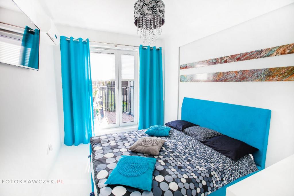 a bedroom with a blue bed and blue curtains at Apartament Nadwiślańska in Krakow