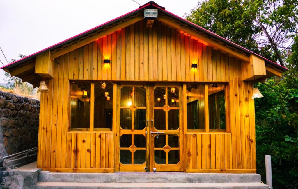 um pequeno edifício de madeira com uma porta grande em Pine Valley Homestay em Nainital
