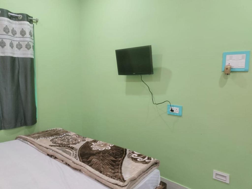 um quarto com uma cama e uma televisão na parede em Maruti Guest House em Puri