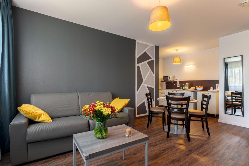 ein Wohnzimmer mit einem Sofa und einem Tisch in der Unterkunft Zenitude Hôtel-Résidences Nantes Métropole in Nantes