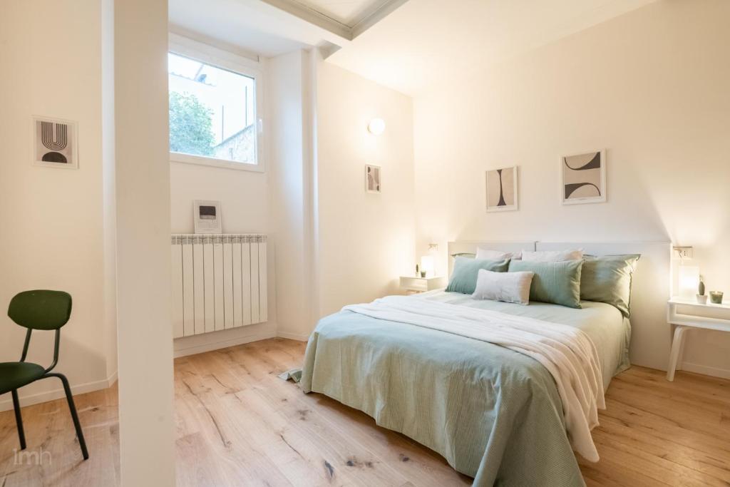 ein weißes Schlafzimmer mit einem Bett und einem Stuhl in der Unterkunft Fortezza Apartment in Florence in Florenz