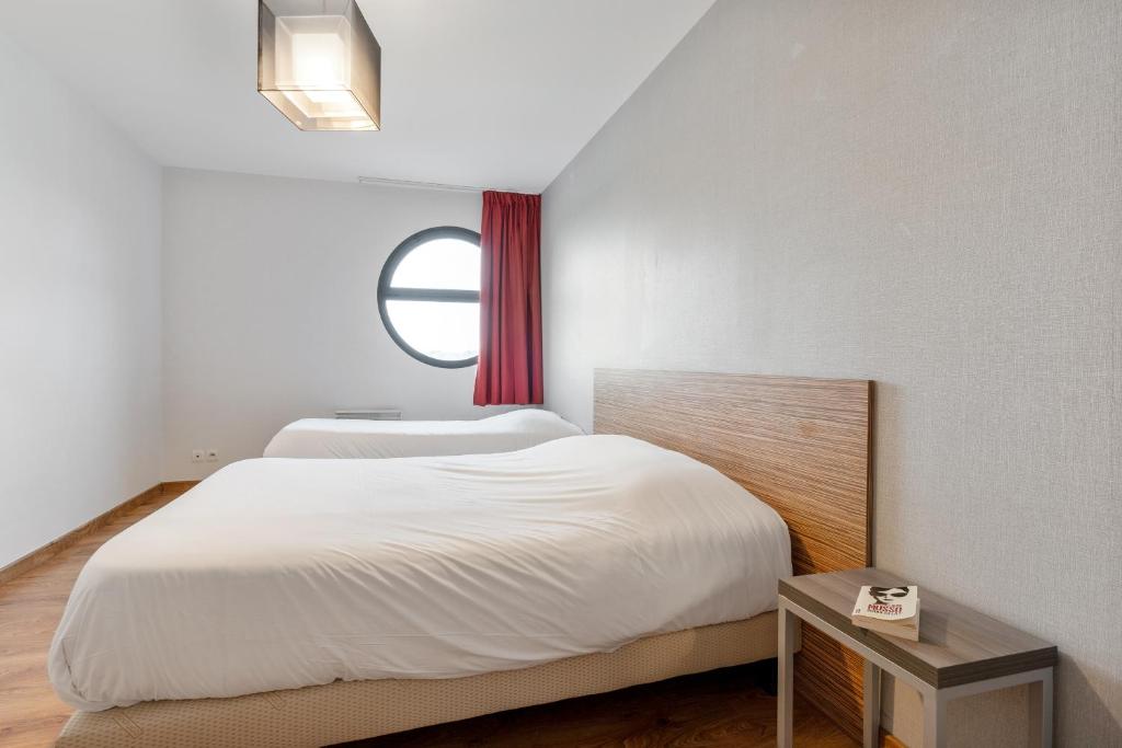 a bedroom with two beds and a window at Zenitude Hôtel-Résidences Nantes Métropole in Nantes