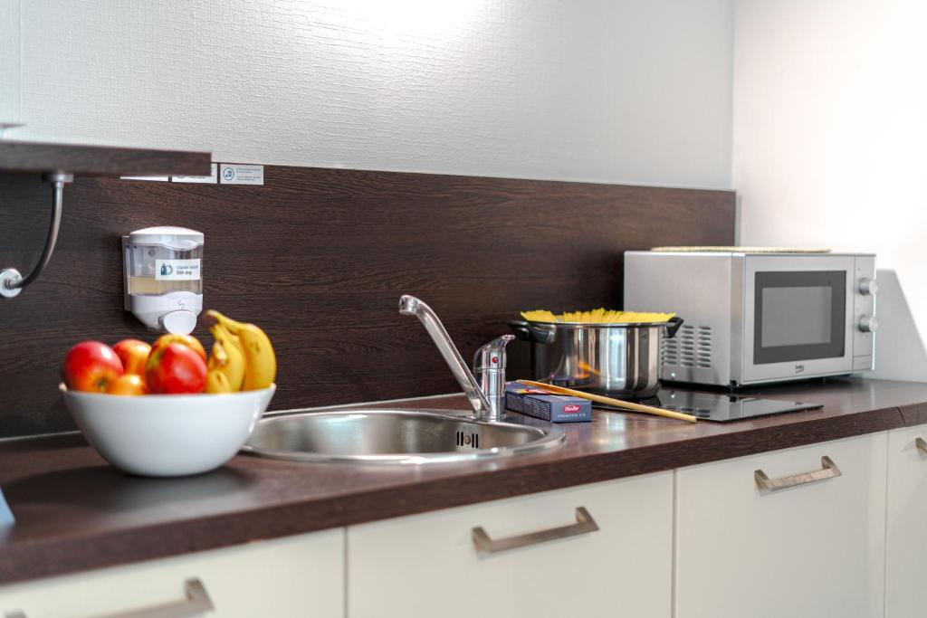 a kitchen counter with a sink and a bowl of fruit at Zenitude Hôtel-Résidences Nantes Métropole in Nantes