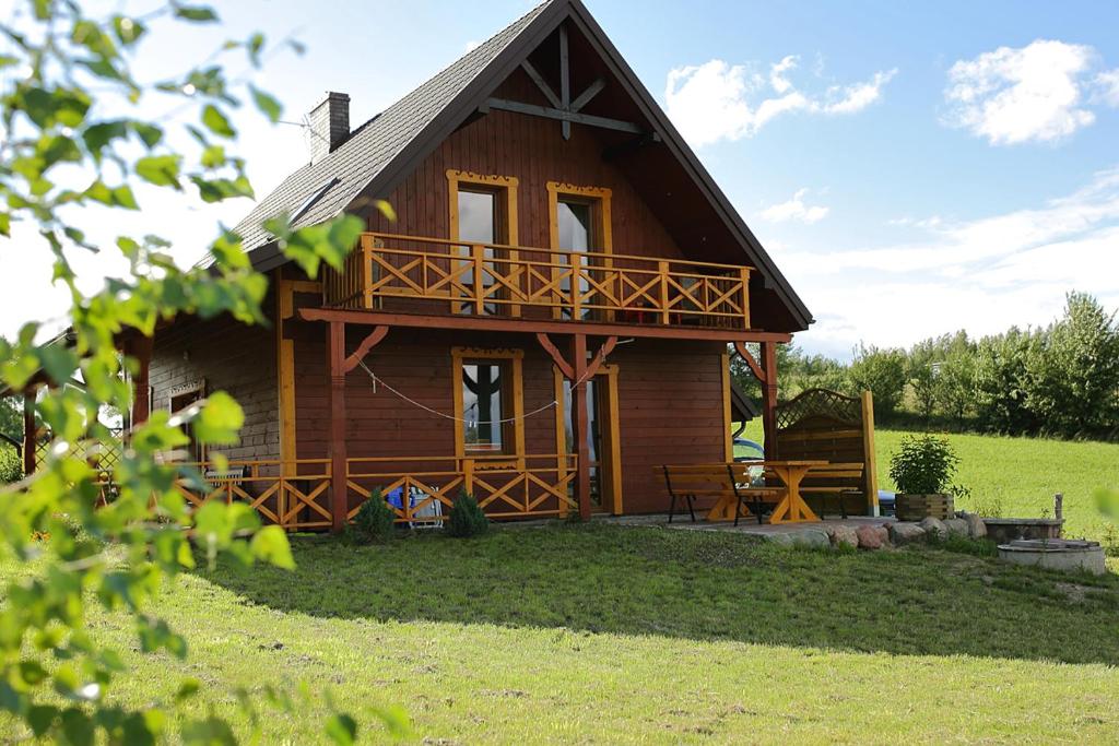 a log cabin with a porch and a balcony at Wakacje w Radziuciach in Sejny