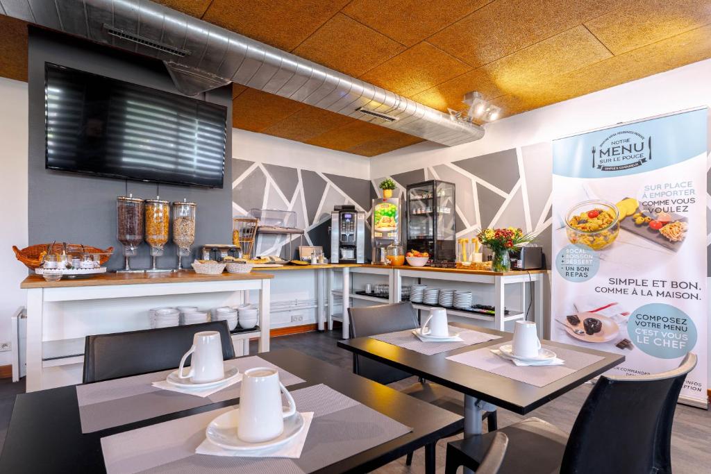 a restaurant with tables and chairs and a kitchen at Zenitude Hôtel-Résidences Nantes Métropole in Nantes